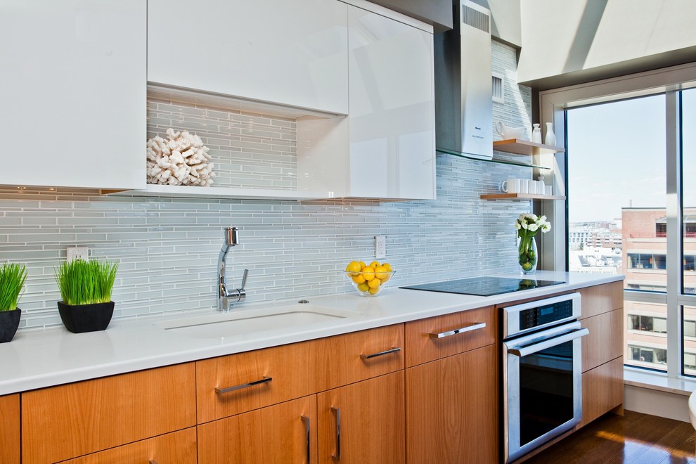 Photo of a contemporary kitchen in Boston with a single-bowl sink, flat-panel cabinets, white cabinets, grey splashback, matchstick tile splashback and stainless steel appliances.