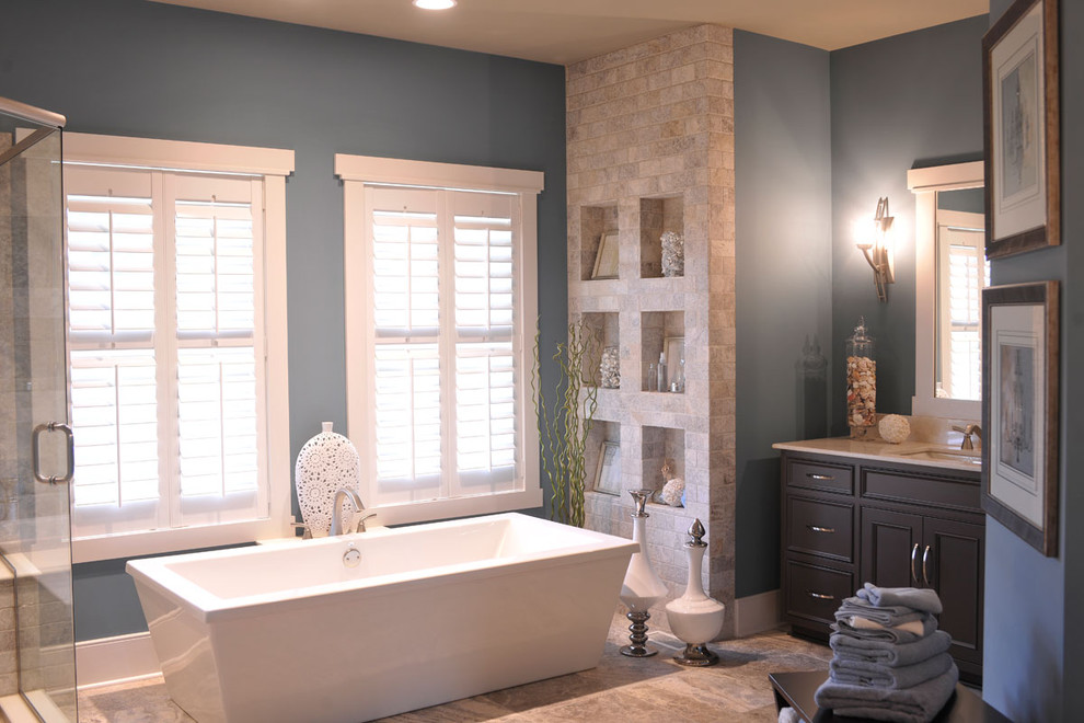 Design ideas for a contemporary master bathroom in Columbus with a freestanding tub, beaded inset cabinets, dark wood cabinets, a corner shower, beige tile, stone tile, blue walls, an undermount sink, brown floor, a hinged shower door, a double vanity and a built-in vanity.