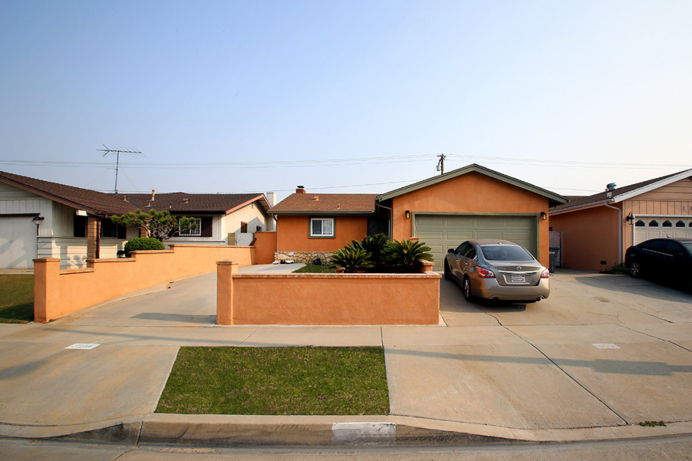 This is an example of a mid-sized arts and crafts one-storey stucco orange house exterior in Los Angeles with a gable roof and a shingle roof.