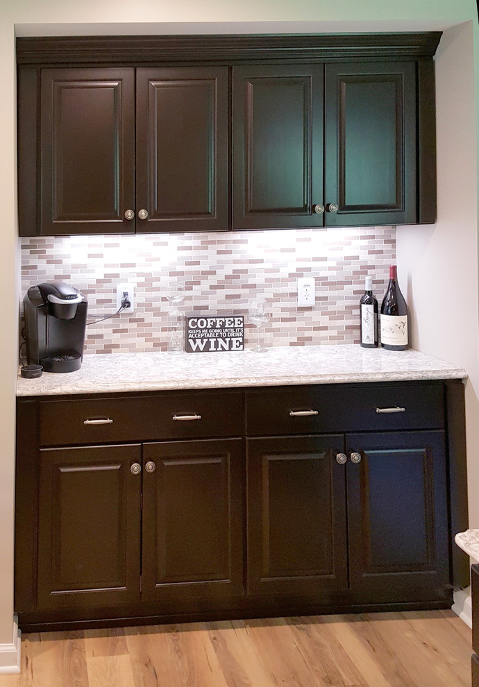 Example of a mid-sized transitional l-shaped light wood floor and brown floor home design design with an undermount sink, raised-panel cabinets, dark wood cabinets, quartz countertops, multicolored backsplash, ceramic backsplash, stainless steel appliances and an island