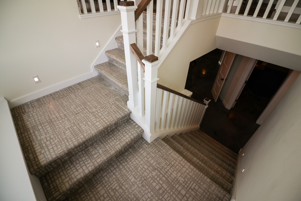 Mid-sized contemporary carpeted u-shaped staircase in Other with carpet risers and wood railing.