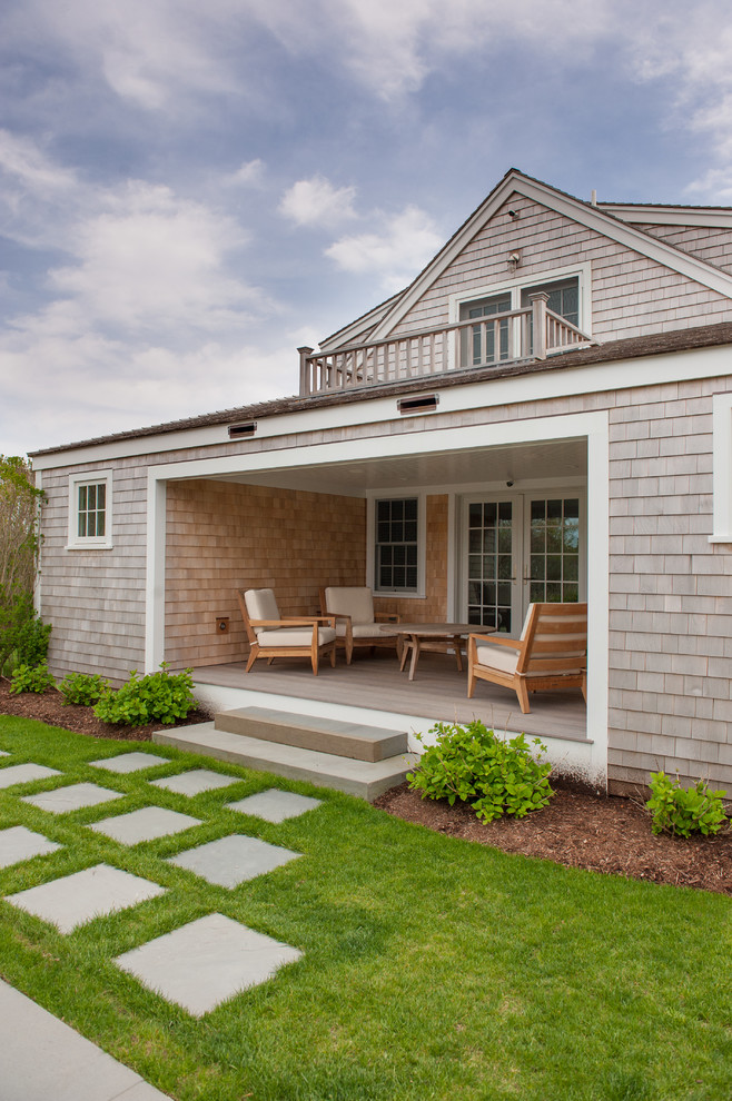 This is an example of a coastal concrete paver back porch design in Boston with a roof extension.