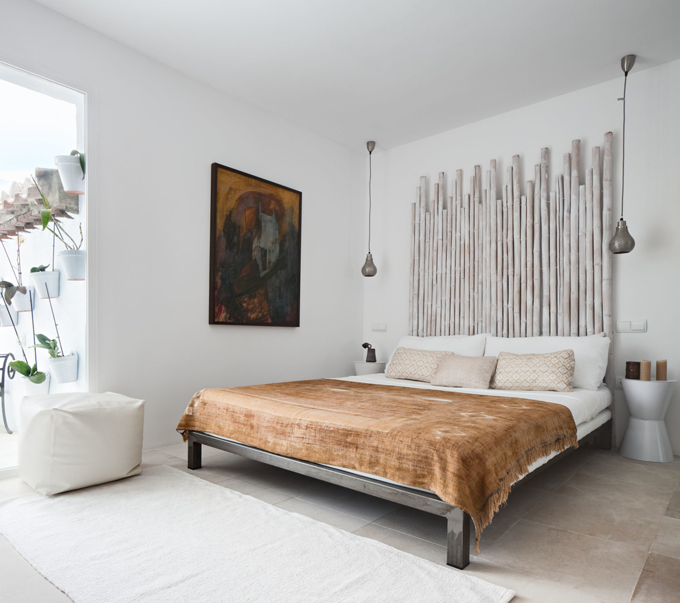 This is an example of a mid-sized mediterranean master bedroom in Malaga with white walls, travertine floors and no fireplace.