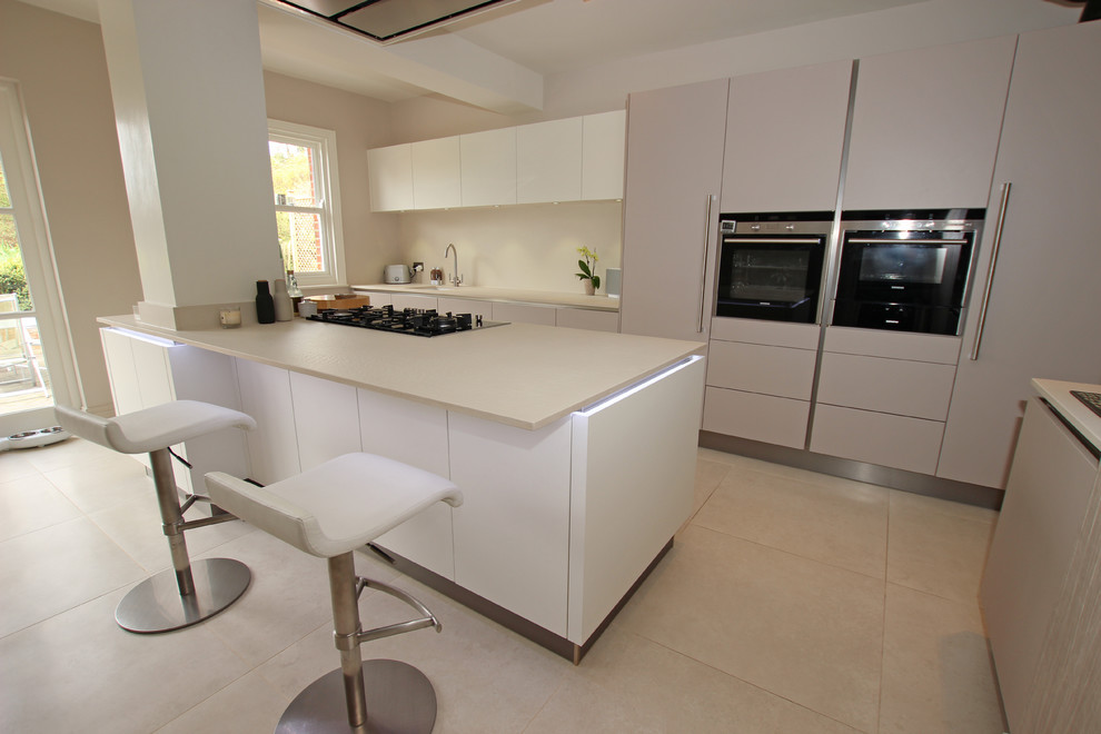 Modern kitchen in London with with island, flat-panel cabinets and quartz benchtops.