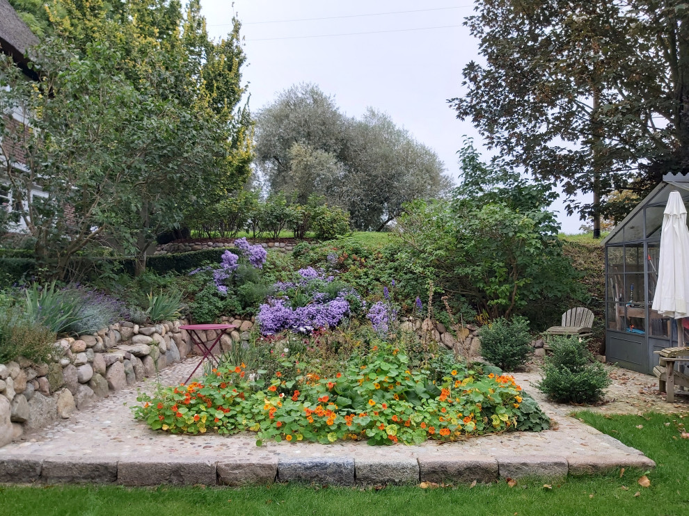 Idéer för en mellanstor lantlig trädgård i delvis sol blomsterrabatt och längs med huset på hösten, med naturstensplattor