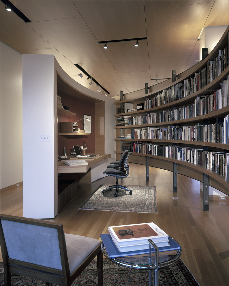 This is an example of a contemporary home office in Minneapolis with white walls, dark hardwood floors and a built-in desk.