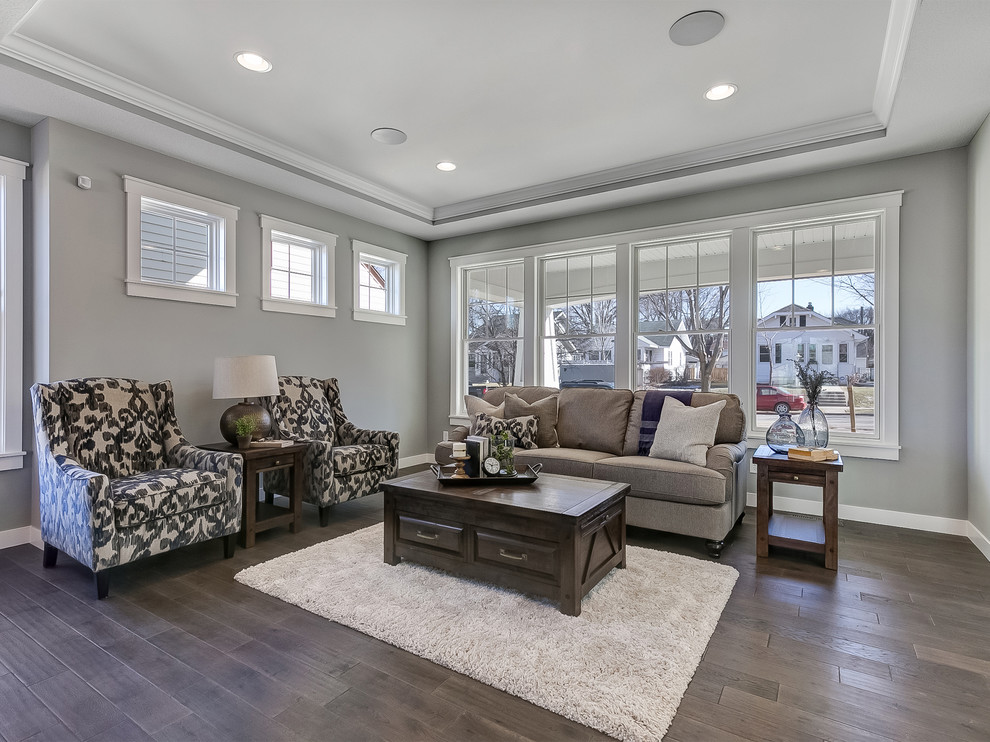 Photo of a mid-sized transitional formal open concept living room in Minneapolis with grey walls, dark hardwood floors, a two-sided fireplace, a wood fireplace surround, a wall-mounted tv and grey floor.