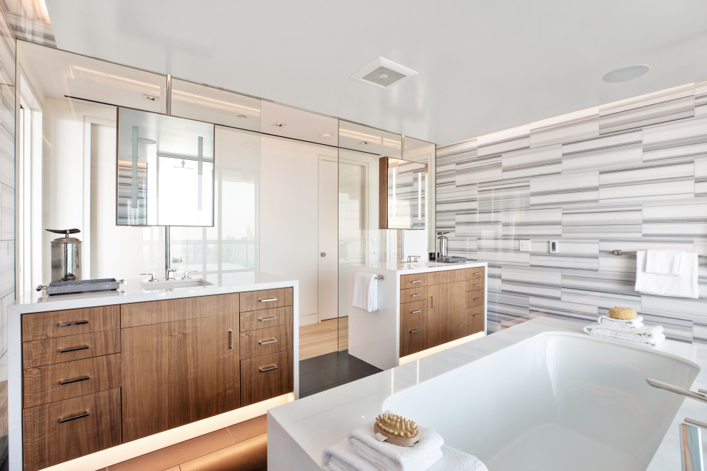 Contemporary bathroom in Los Angeles with flat-panel cabinets, medium wood cabinets, an undermount tub, black and white tile, white walls, an undermount sink, black floor and white benchtops.