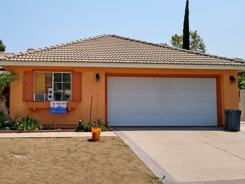 Inspiration for an orange house exterior in Los Angeles with a tile roof and a brown roof.