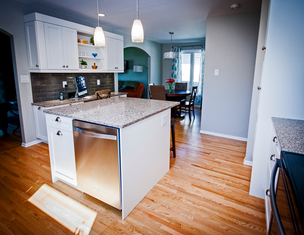 Inspiration for a mid-sized transitional l-shaped light wood floor eat-in kitchen remodel with a double-bowl sink, shaker cabinets, white cabinets, quartz countertops, brown backsplash, ceramic backsplash, stainless steel appliances and an island