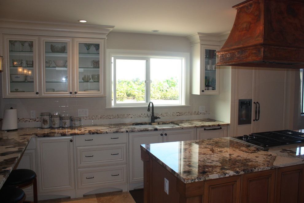 Inspiration for a mid-sized rustic l-shaped porcelain tile and beige floor kitchen pantry remodel in Vancouver with an undermount sink, raised-panel cabinets, white cabinets, granite countertops, beige backsplash, ceramic backsplash, stainless steel appliances and an island