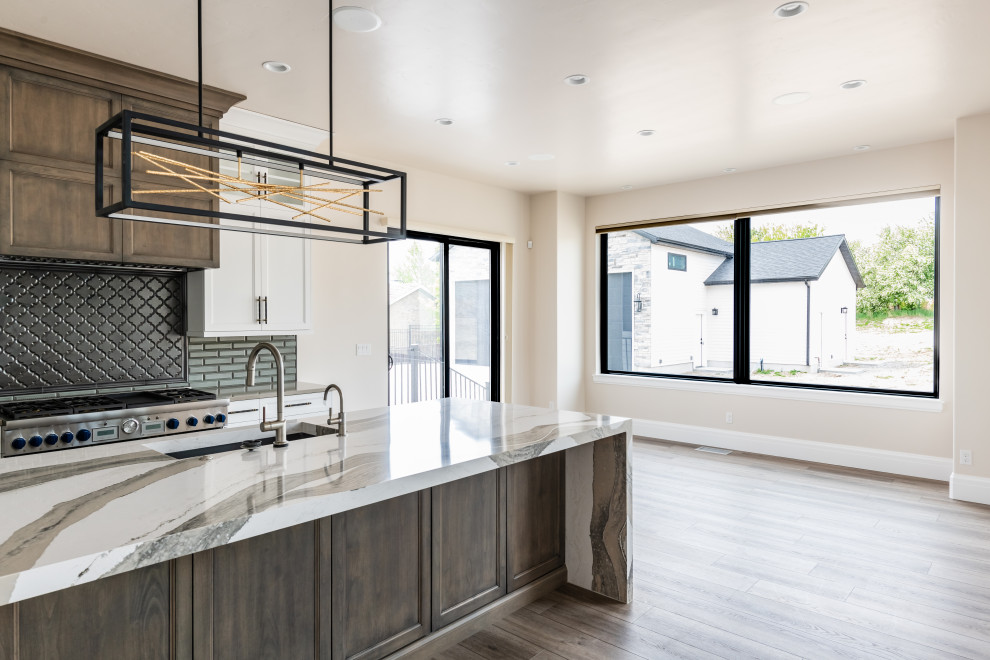 Inspiration for a large classic l-shaped open plan kitchen in Salt Lake City with a submerged sink, white cabinets, engineered stone countertops, grey splashback, ceramic splashback, stainless steel appliances, vinyl flooring, an island, brown floors, white worktops and recessed-panel cabinets.