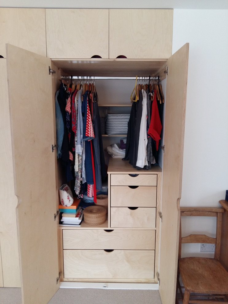 This is an example of an expansive scandinavian storage and wardrobe in Cornwall with flat-panel cabinets, light wood cabinets, carpet and grey floor.