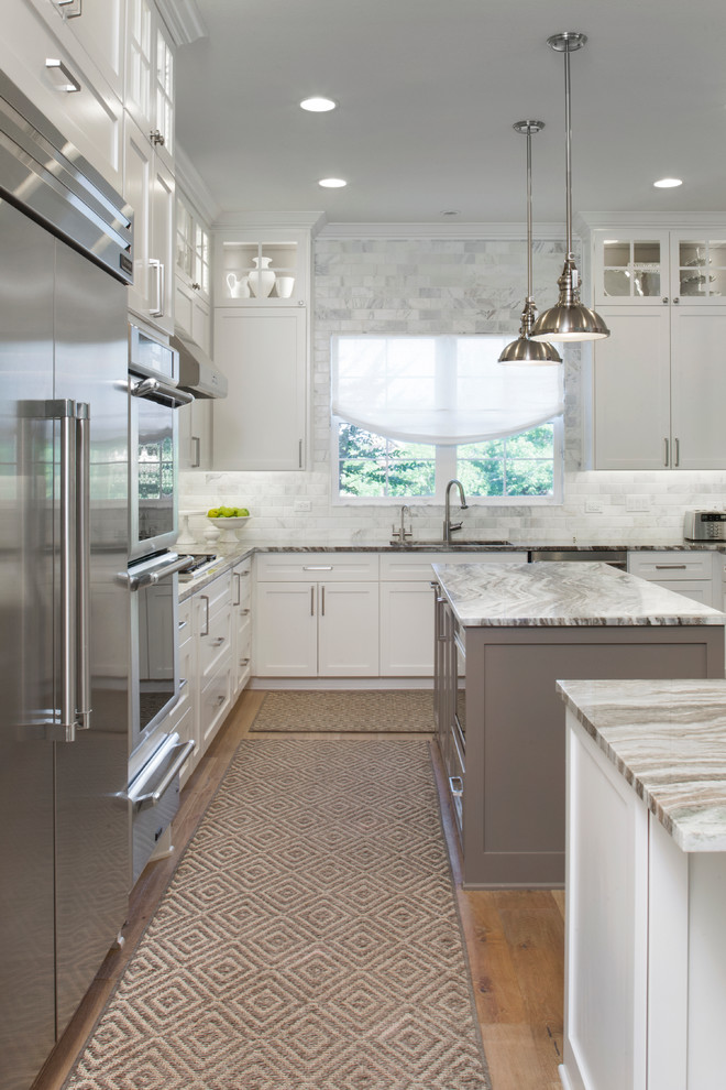 Design ideas for a traditional u-shaped kitchen in Raleigh with shaker cabinets, white cabinets, white splashback, stainless steel appliances, medium hardwood floors and with island.