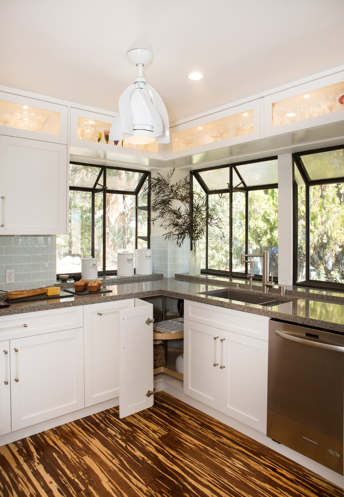 Large modern u-shaped eat-in kitchen in Los Angeles with an undermount sink, shaker cabinets, white cabinets, quartz benchtops, glass tile splashback, stainless steel appliances, bamboo floors, a peninsula, blue splashback and brown floor.