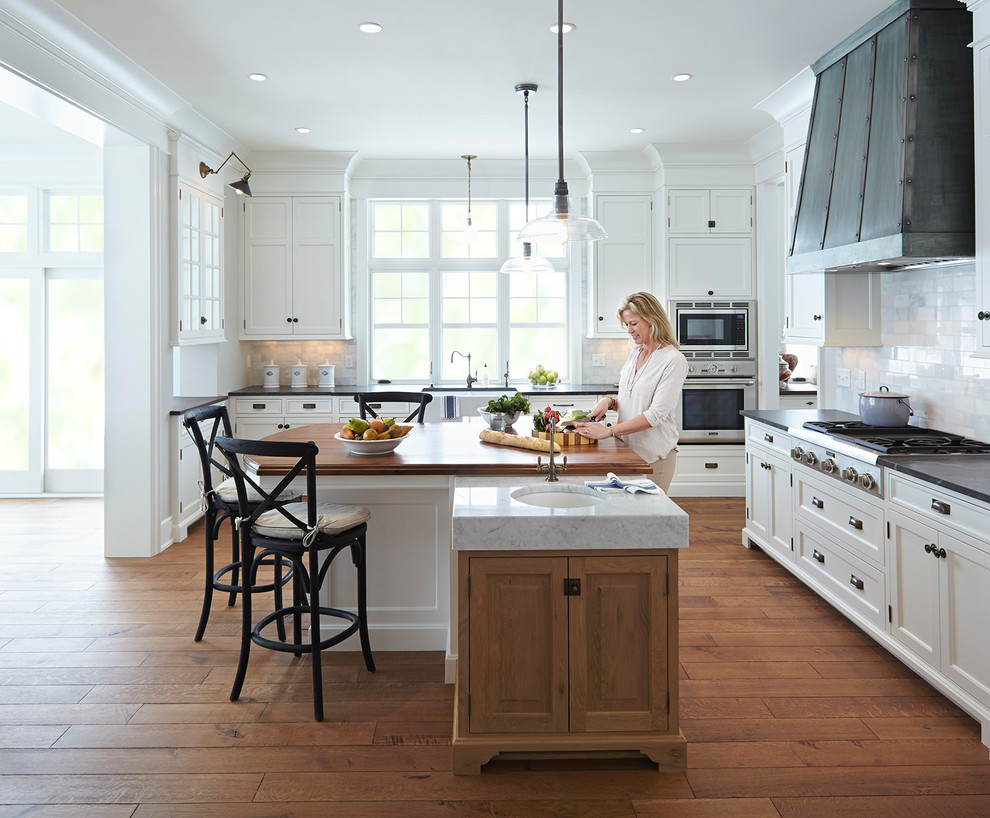 Inspiration for a large beach style open plan kitchen in Minneapolis with a farmhouse sink, recessed-panel cabinets, white cabinets, white splashback, subway tile splashback and stainless steel appliances.