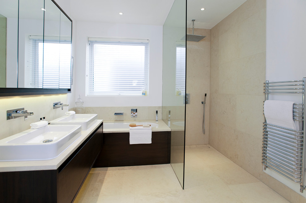 Photo of a mid-sized contemporary master bathroom in Dorset with a vessel sink, flat-panel cabinets, dark wood cabinets, an undermount tub, a corner shower, beige tile, white walls and beige floor.