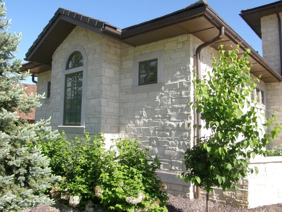 This is an example of a traditional one-storey white house exterior in Other with stone veneer.