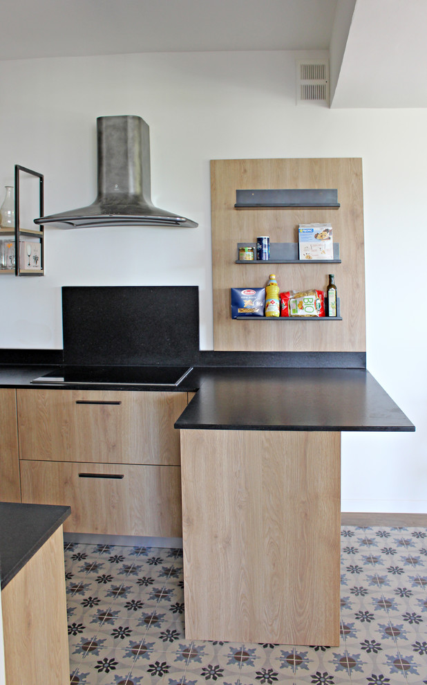 Photo of a mid-sized industrial l-shaped open plan kitchen in Other with an integrated sink, beaded inset cabinets, light wood cabinets, granite benchtops, black splashback, ceramic floors, a peninsula, multi-coloured floor and black benchtop.