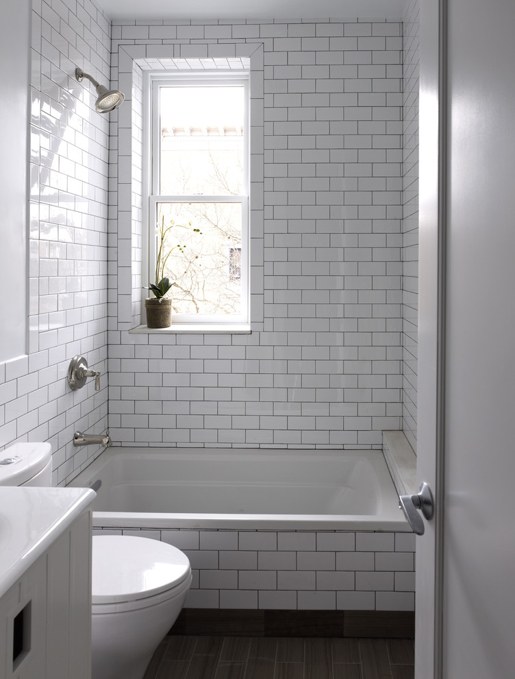 Mid-sized contemporary 3/4 bathroom in New York with white cabinets, an alcove tub, a shower/bathtub combo, a two-piece toilet, white tile, subway tile, white walls, marble floors, a console sink and flat-panel cabinets.