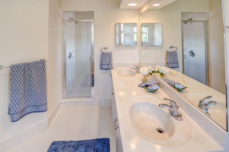 This is an example of a large eclectic master bathroom in Miami with an integrated sink, flat-panel cabinets, white cabinets, limestone benchtops, a hot tub, a corner shower, a one-piece toilet, beige tile, ceramic tile, beige walls and ceramic floors.