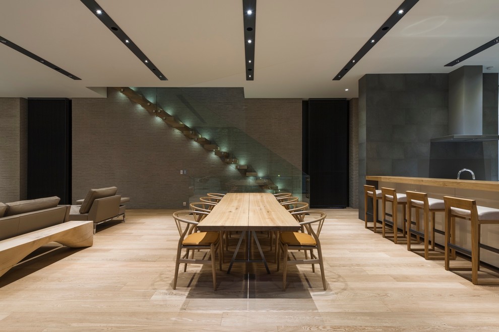 Modern open plan dining in Tokyo with grey walls and light hardwood floors.