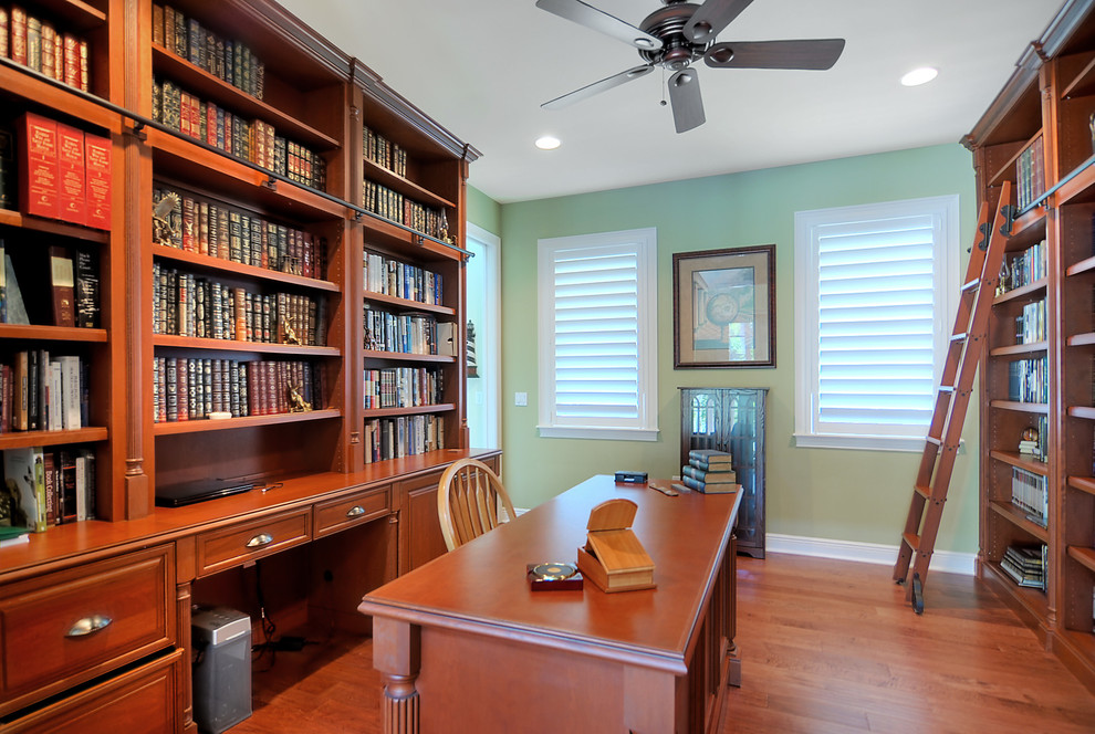 Design ideas for a large traditional home office in Orlando with a freestanding desk, a library, brown walls, medium hardwood floors, no fireplace and brown floor.