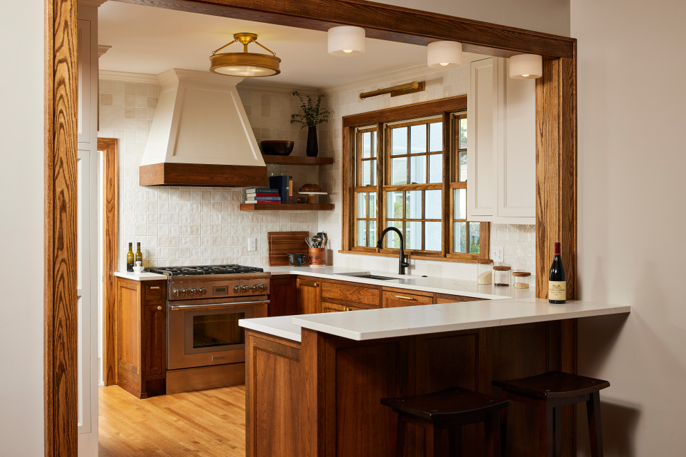 Mid-sized transitional u-shaped medium tone wood floor kitchen photo in Minneapolis with an undermount sink, recessed-panel cabinets, dark wood cabinets, quartzite countertops, ceramic backsplash and stainless steel appliances