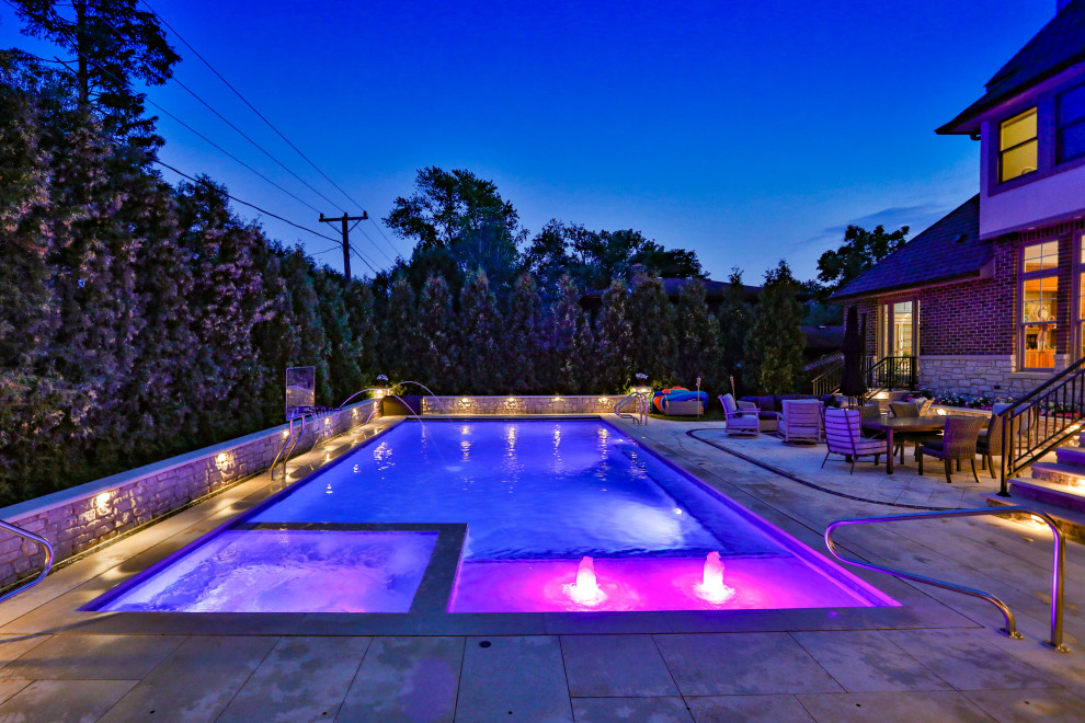 Imagen de piscina alargada tradicional de tamaño medio rectangular en patio trasero con privacidad y adoquines de piedra natural