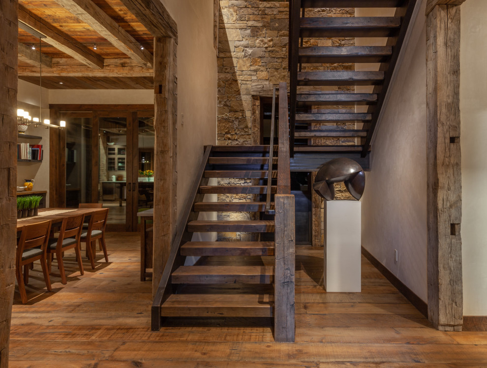 Photo of a large country wood u-shaped staircase in Denver with open risers and metal railing.