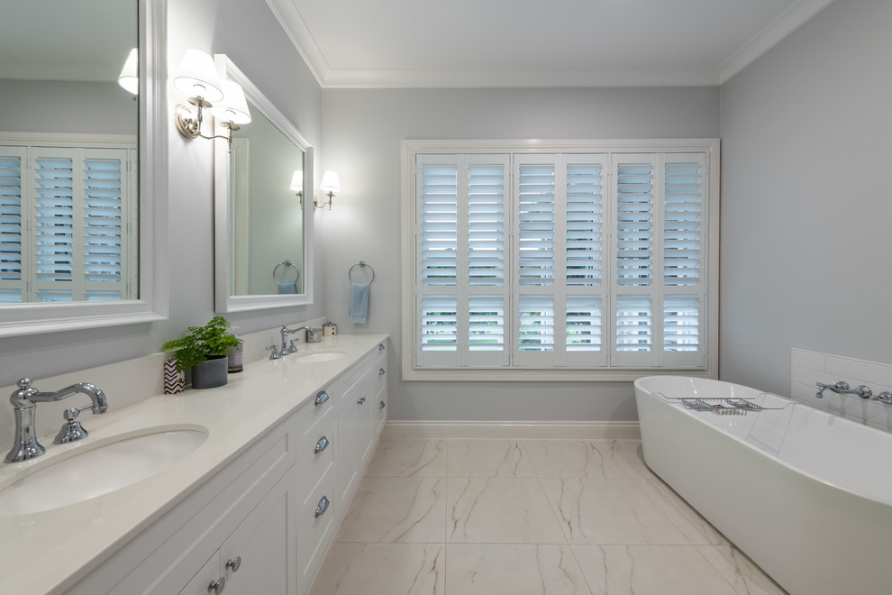 Photo of a large contemporary bathroom in Gold Coast - Tweed with shaker cabinets, white cabinets, a freestanding tub, an undermount sink, engineered quartz benchtops and white benchtops.