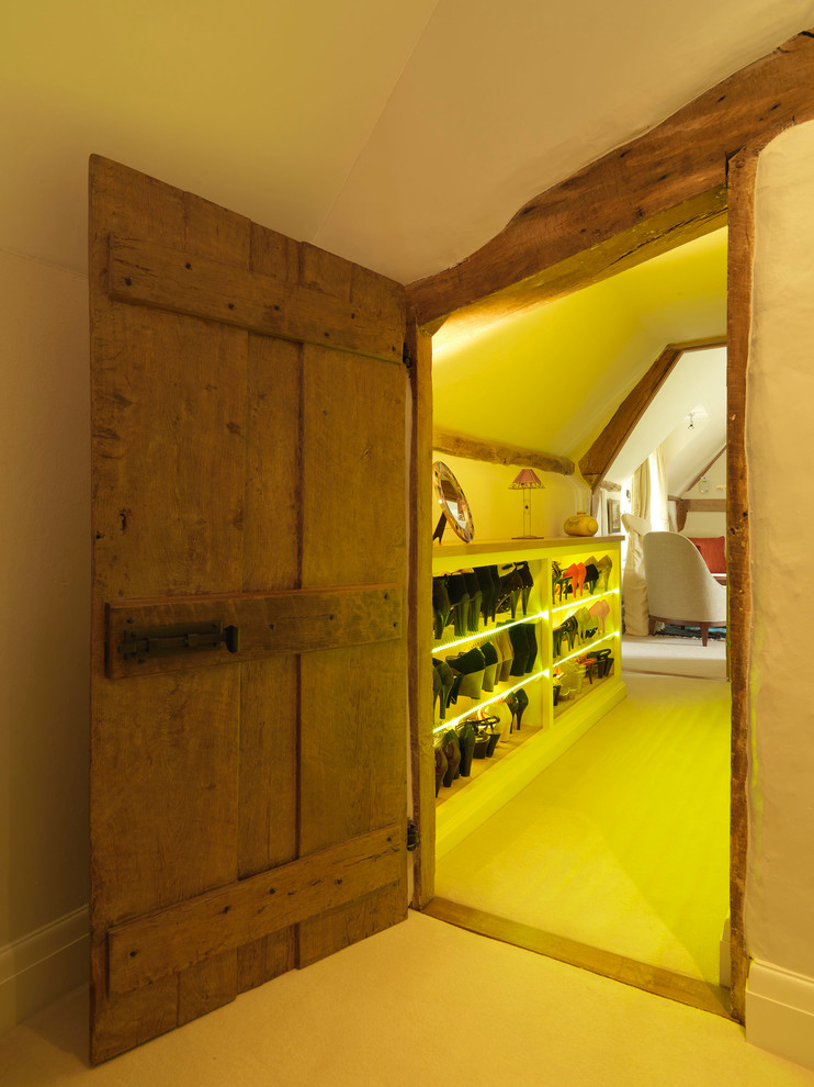 This is an example of a mid-sized country women's walk-in wardrobe in Hampshire with open cabinets, white cabinets and yellow floor.