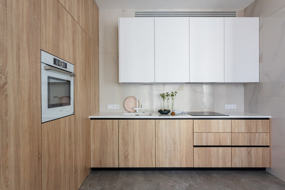 Example of a mid-sized trendy l-shaped porcelain tile and gray floor eat-in kitchen design in Yekaterinburg with an integrated sink, flat-panel cabinets, light wood cabinets, quartz countertops, beige backsplash, porcelain backsplash, white appliances, no island and white countertops
