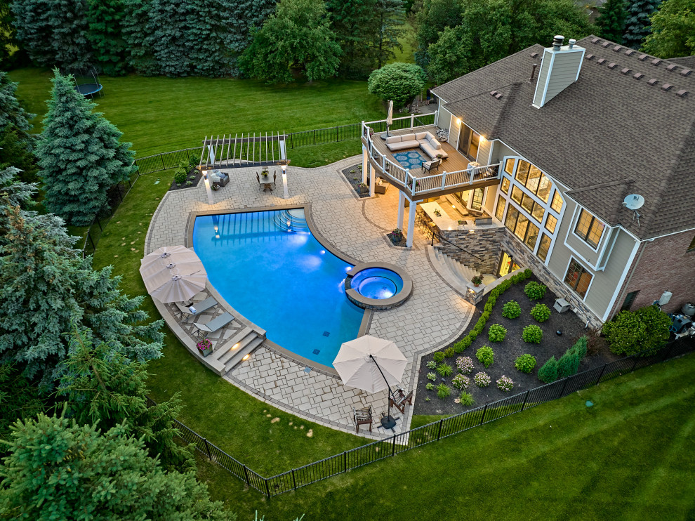 Design ideas for a large contemporary backyard custom-shaped pool in Detroit with a hot tub and concrete pavers.