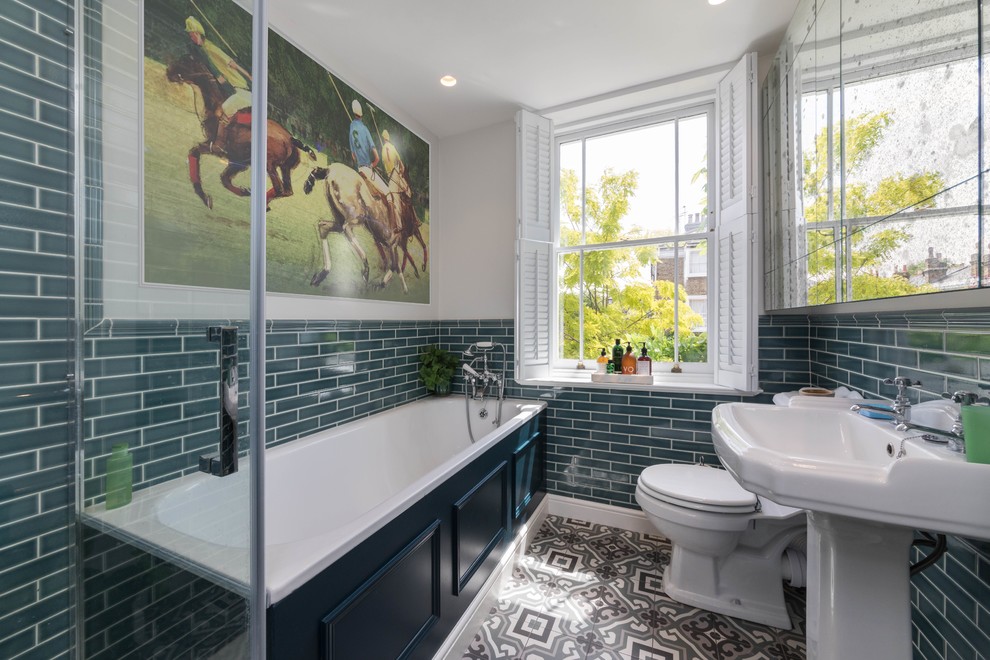 Mid-sized traditional kids bathroom in Other with a drop-in tub, a curbless shower, a two-piece toilet, green tile, subway tile, grey walls, ceramic floors, a pedestal sink, multi-coloured floor, a hinged shower door, a single vanity and a freestanding vanity.