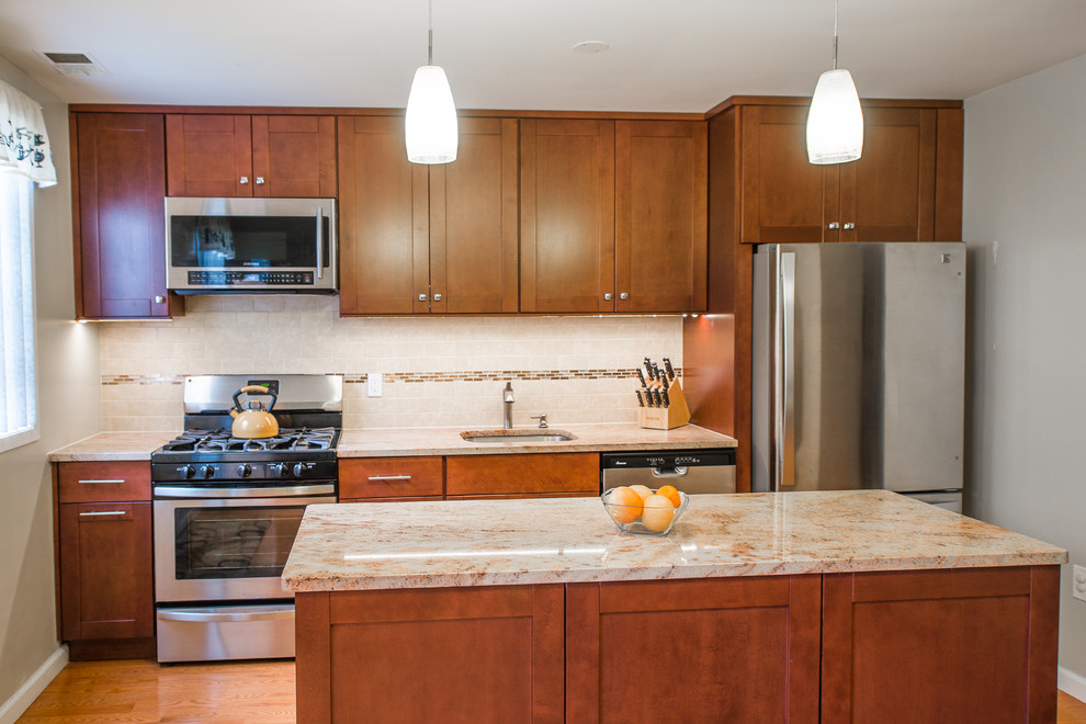 This is an example of a mid-sized transitional single-wall eat-in kitchen in New York with an undermount sink, shaker cabinets, medium wood cabinets, granite benchtops, brown splashback, stainless steel appliances, medium hardwood floors, with island and stone tile splashback.