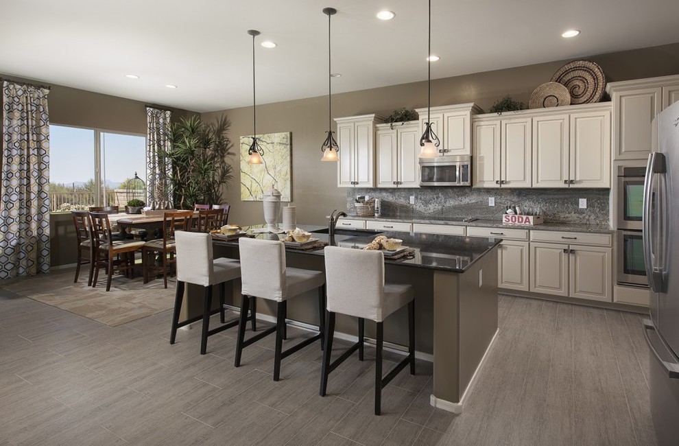 Example of a mid-sized transitional l-shaped ceramic tile and brown floor eat-in kitchen design with an undermount sink, raised-panel cabinets, white cabinets, granite countertops, gray backsplash, stone slab backsplash, stainless steel appliances and an island
