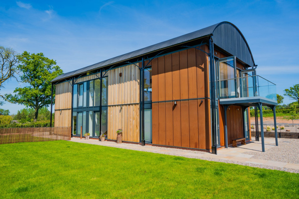 Large modern two-storey orange house exterior in West Midlands with metal siding and a metal roof.