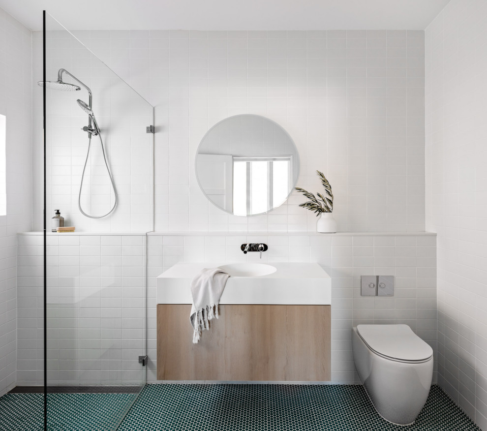Свежая идея для дизайна: ванная комната среднего размера в стиле модернизм с плоскими фасадами, светлыми деревянными фасадами, открытым душем, унитазом-моноблоком, белой плиткой, керамической плиткой, белыми стенами, бетонным полом, монолитной раковиной, столешницей из искусственного камня, зеленым полом, открытым душем, белой столешницей, тумбой под две раковины и подвесной тумбой - отличное фото интерьера