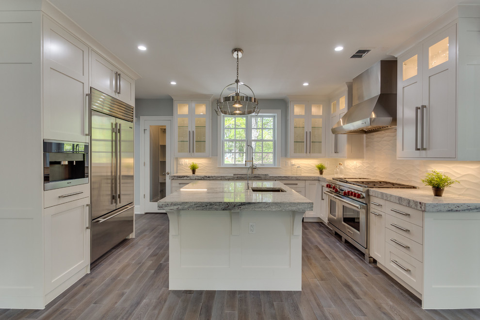 Inspiration for a large transitional l-shaped medium tone wood floor open concept kitchen remodel in DC Metro with a single-bowl sink, shaker cabinets, white cabinets, marble countertops, white backsplash, porcelain backsplash, stainless steel appliances and an island