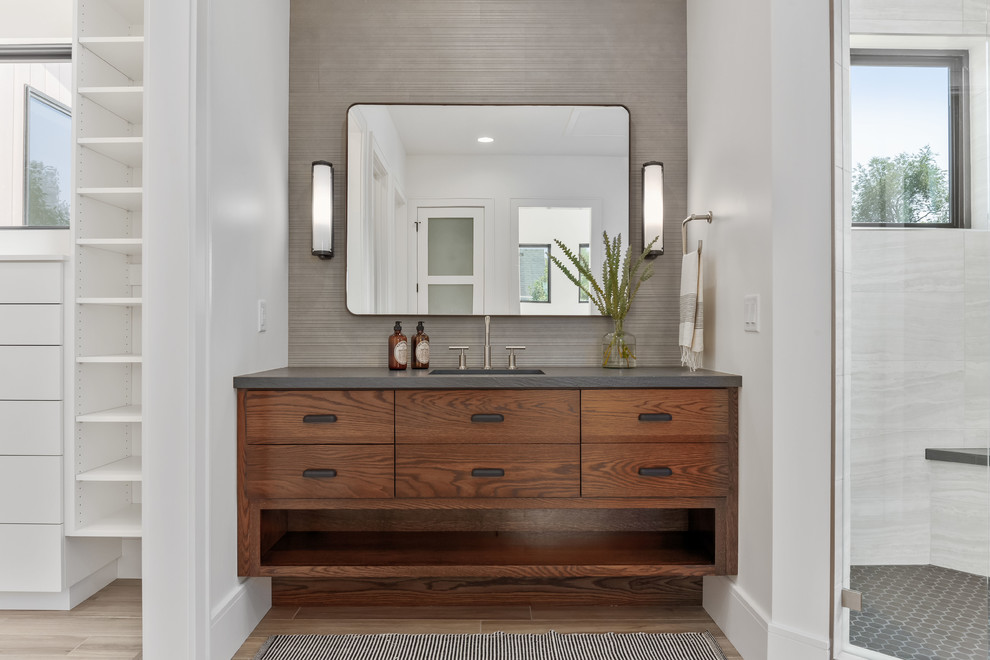 Inspiration for a large contemporary master bathroom in Salt Lake City with flat-panel cabinets, medium wood cabinets, a corner shower, a one-piece toilet, gray tile, porcelain tile, white walls, porcelain floors, an undermount sink, quartzite benchtops, beige floor, a hinged shower door and grey benchtops.