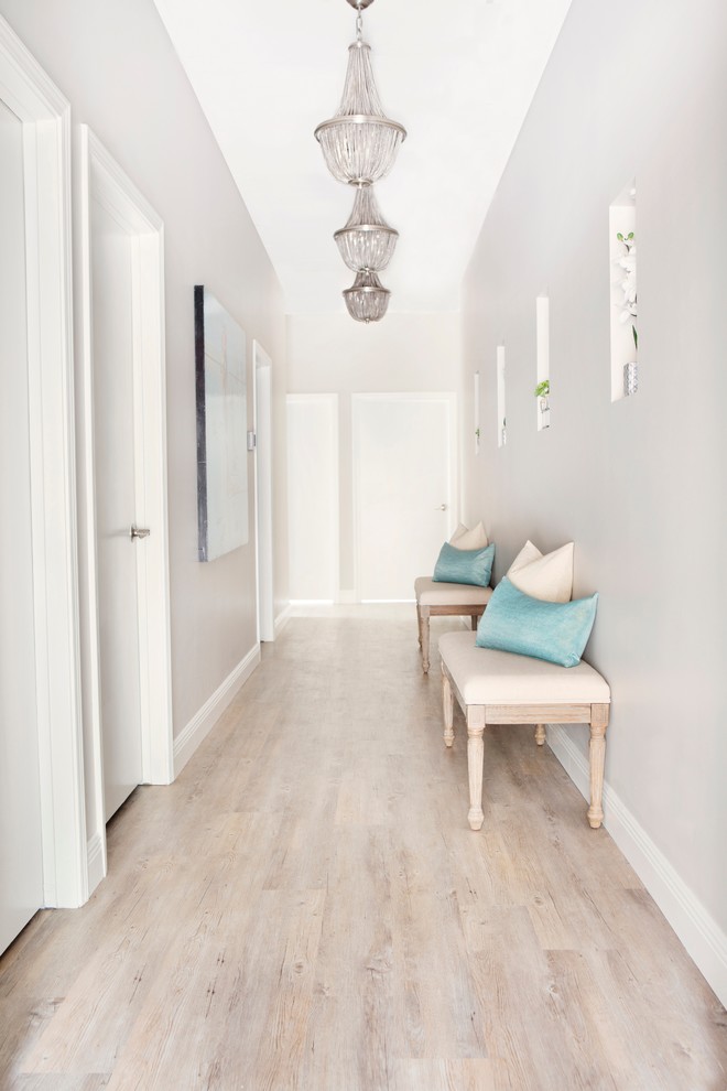 Expansive transitional hallway in Austin with grey walls and light hardwood floors.