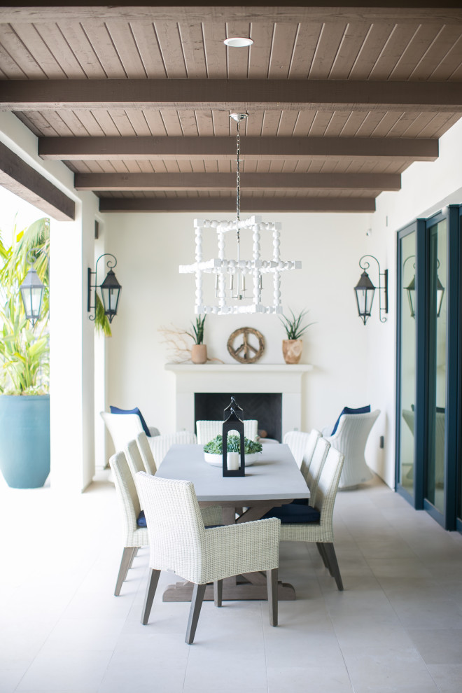 Inspiration for a beach style patio in Orange County with with fireplace and a roof extension.