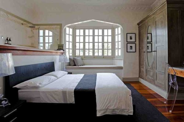 Small eclectic master bedroom in Brisbane with white walls and light hardwood floors.