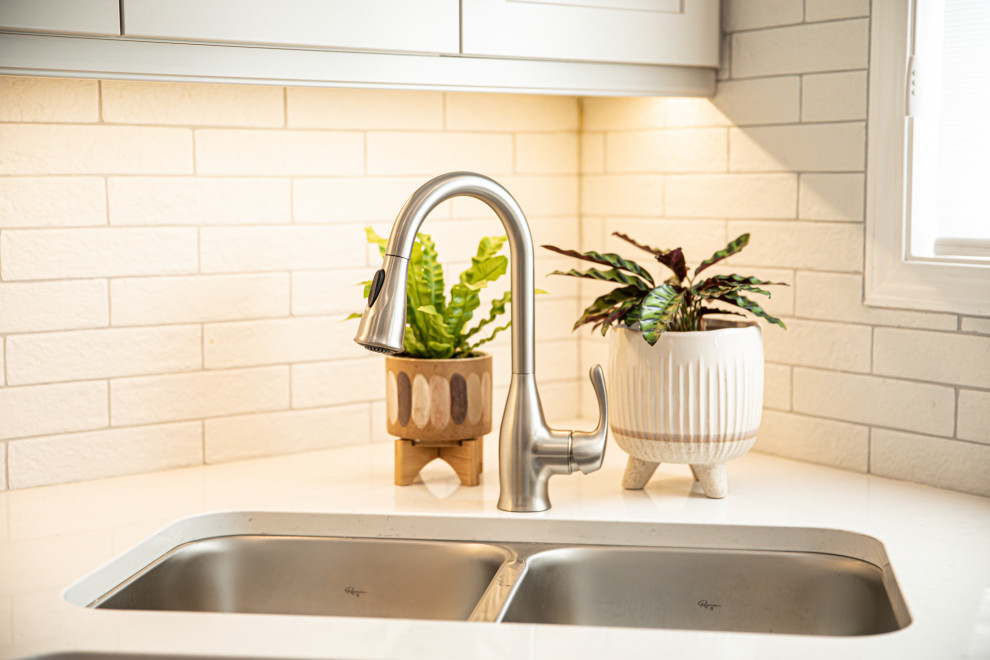 Mid-sized transitional l-shaped vinyl floor and brown floor eat-in kitchen photo in Edmonton with an undermount sink, shaker cabinets, beige cabinets, quartz countertops, white backsplash, ceramic backsplash, stainless steel appliances, no island and white countertops