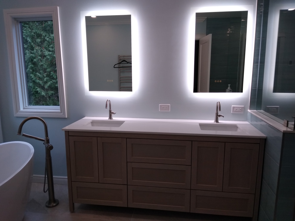 This is an example of a mid-sized contemporary master bathroom in Toronto with shaker cabinets, light wood cabinets, a freestanding tub, a corner shower, a one-piece toilet, blue tile, porcelain tile, blue walls, porcelain floors, an undermount sink, engineered quartz benchtops, beige floor, an open shower, white benchtops, a niche, a double vanity and a freestanding vanity.