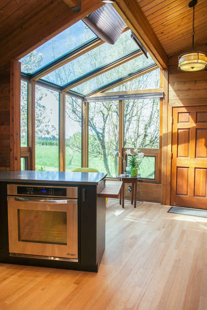 Large mountain style l-shaped light wood floor open concept kitchen photo in Portland with shaker cabinets, black cabinets, stainless steel appliances and an island