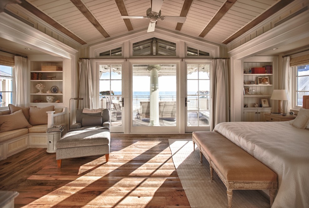 This is an example of a large beach style bedroom in Other with beige walls, medium hardwood floors and brown floor.