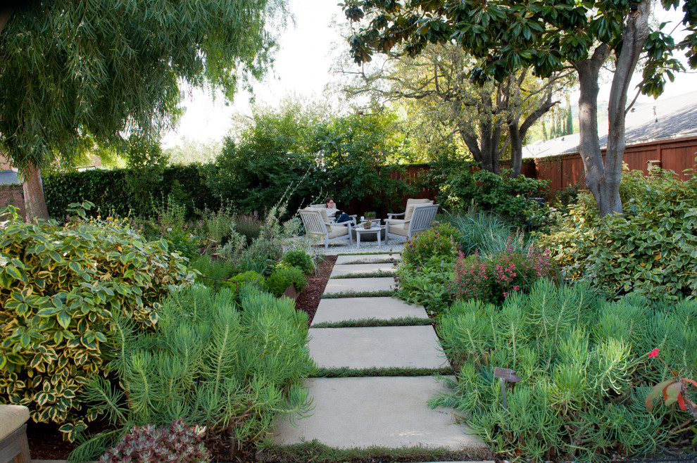Large contemporary backyard shaded xeriscape in Los Angeles with with flowerbed, mulch and a wood fence for spring.