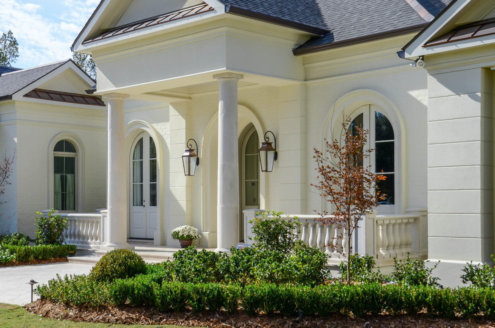Photo of a large traditional one-storey white exterior in New Orleans with stone veneer and a gable roof.